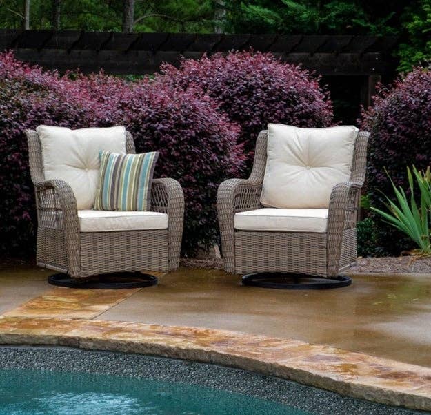 the two wicker chairs with tan cushions next to a pool