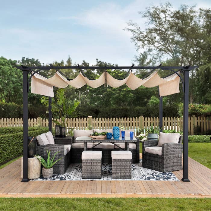 the metal pergola with an adjustable canopy in a yard
