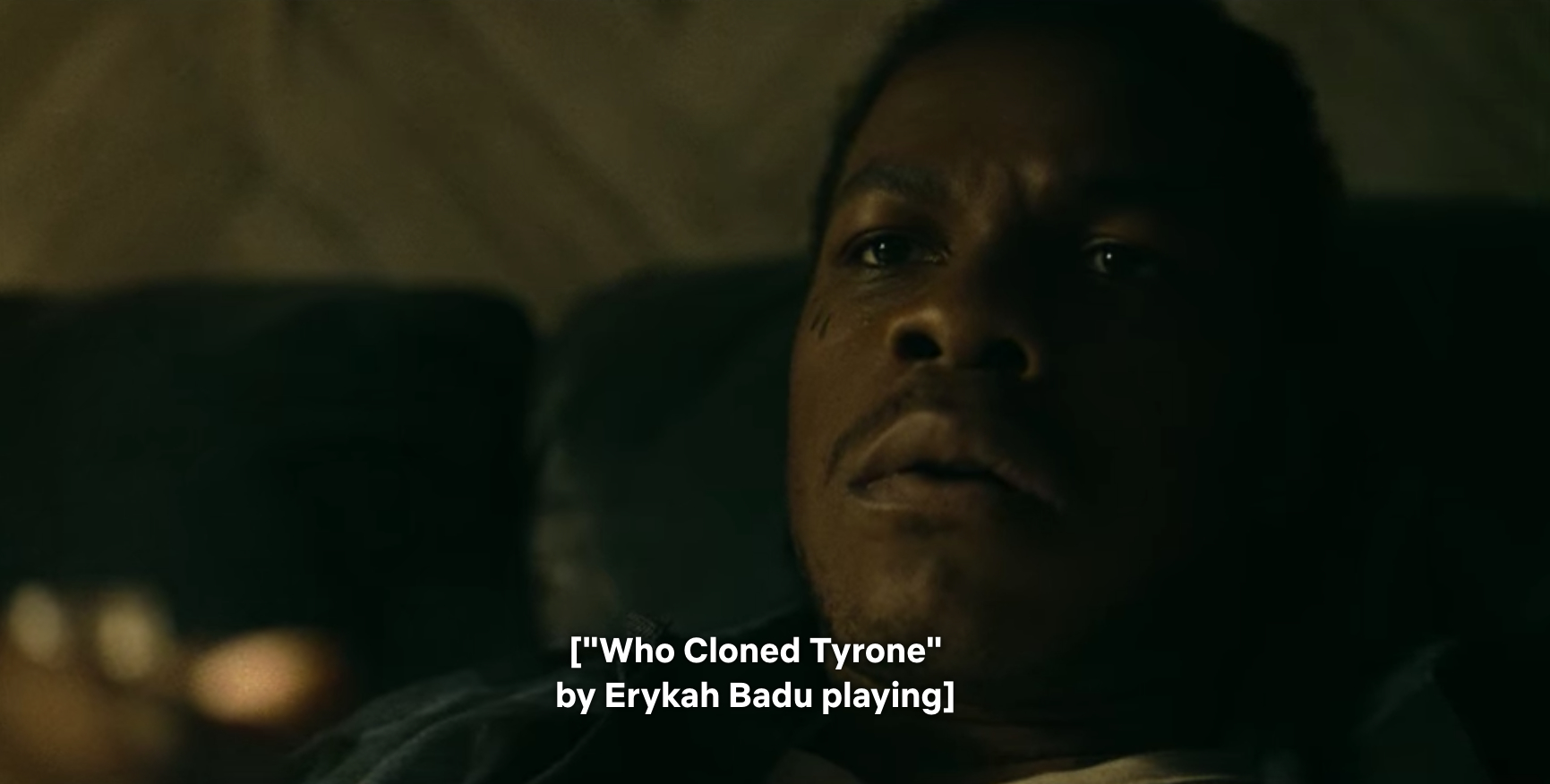 Man watching television with a confused look on his face as the words Who Cloned Tyrone appear on the screen