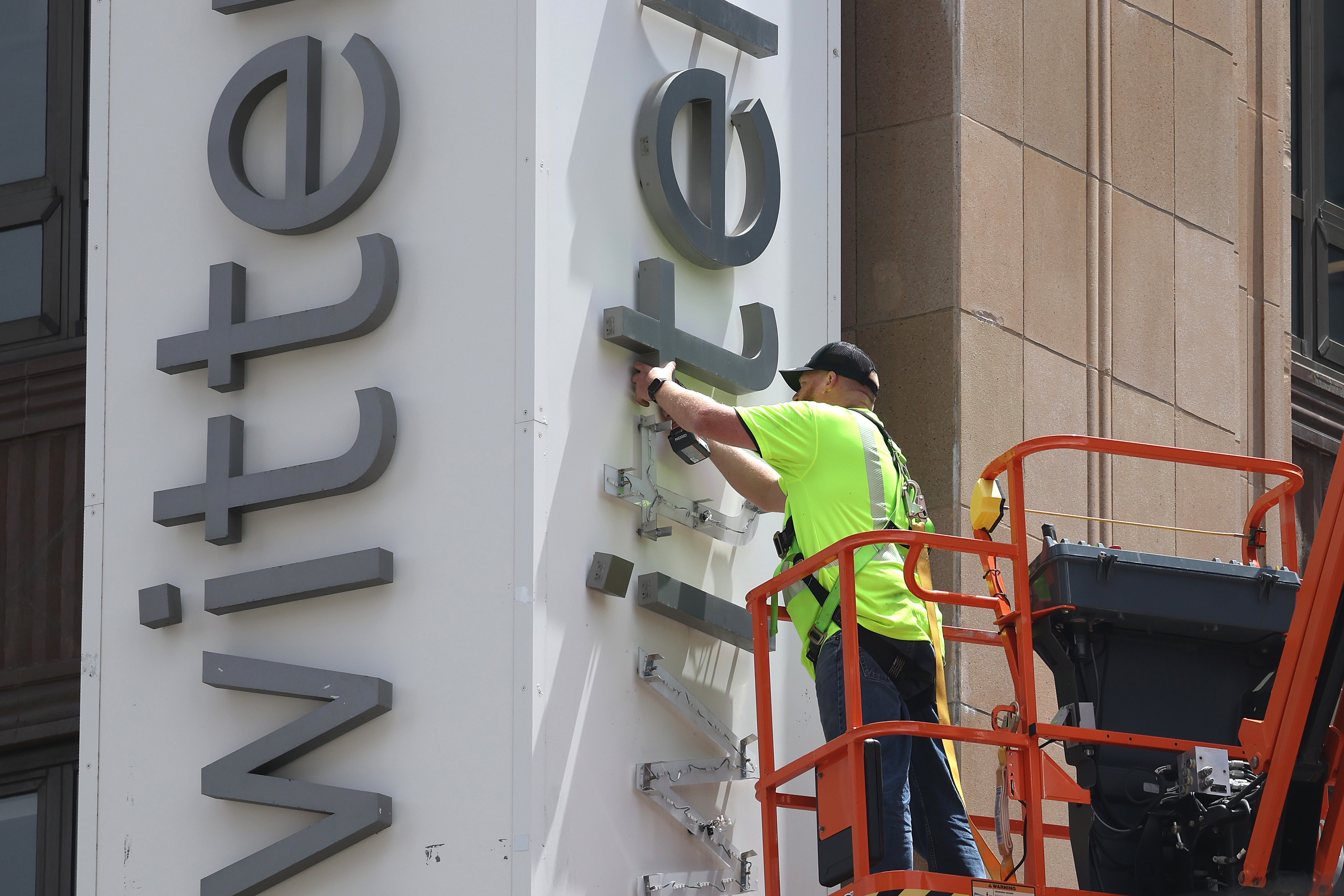 A worker taking down the twitter sign from the building