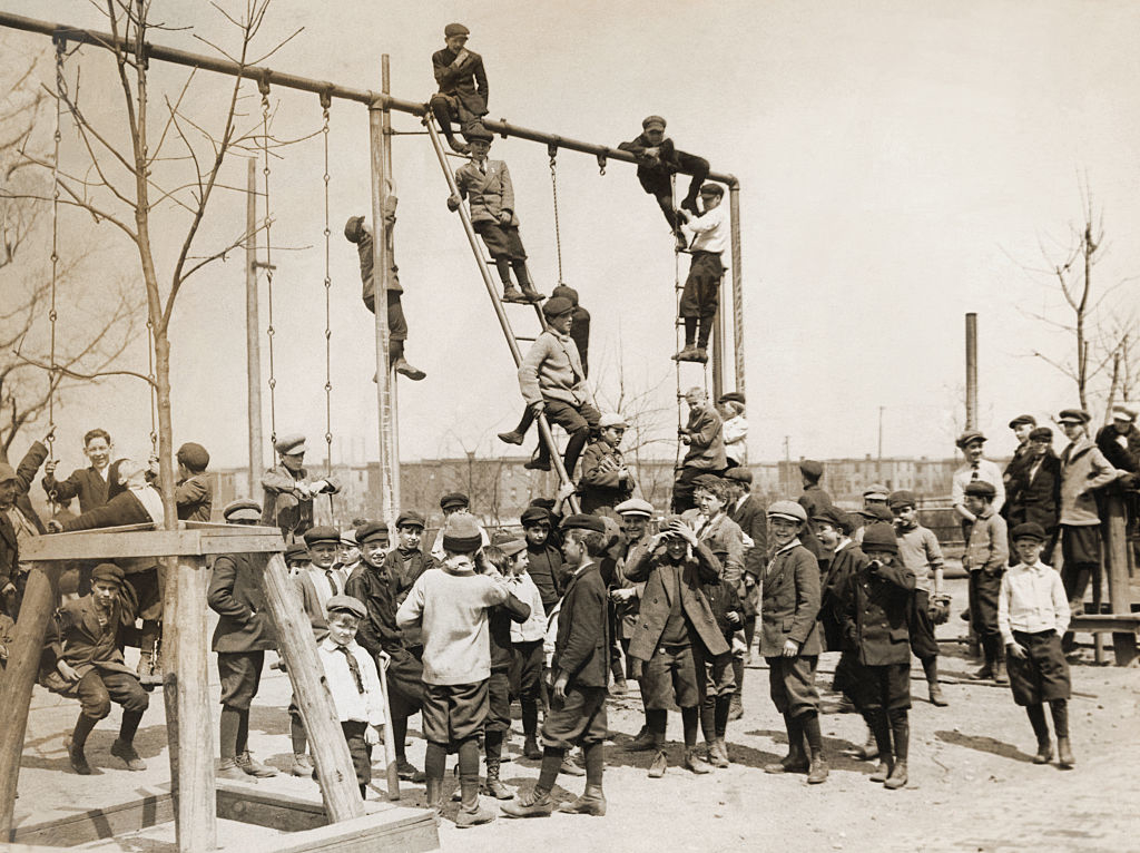Boys and men climbing ladders to poles in a playground
