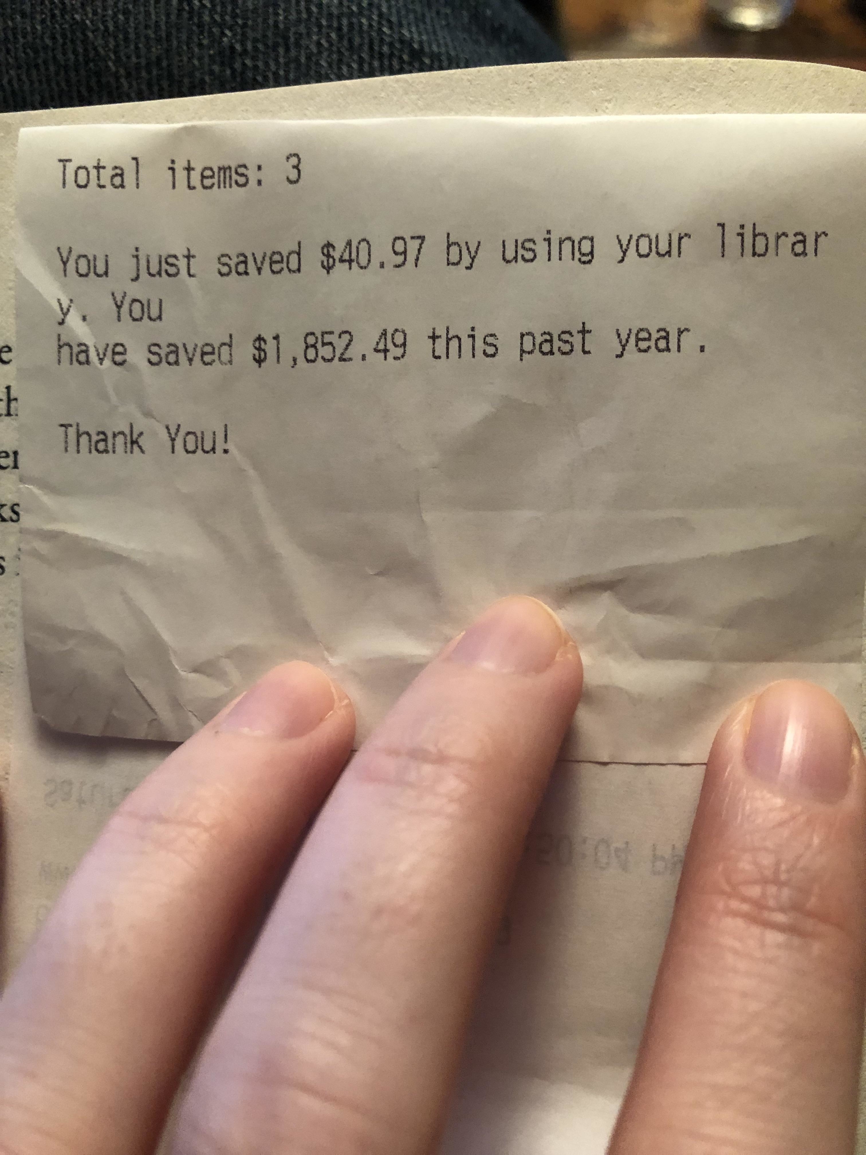 A handheld receipt showing the message &quot;You just saved $41 by using your library; you have saved $1,853 this past year; thank you!&quot;