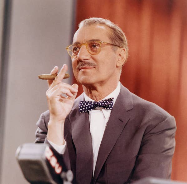 American comedian Groucho Marx holds a cigar as he hosts an episode of the television show 'You Bet Your Life'
