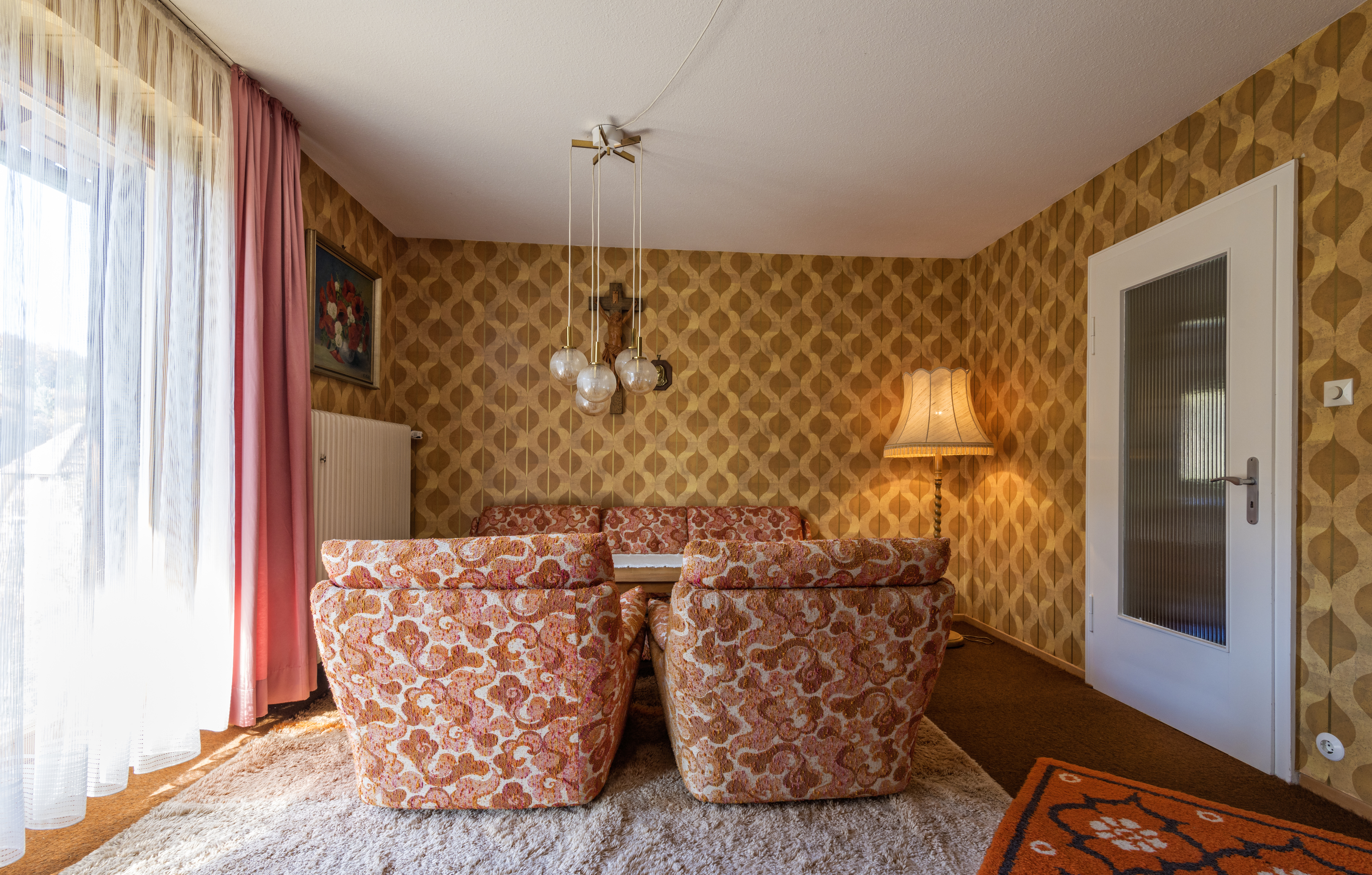 A room with &#x27;70s style furniture and wallpaper