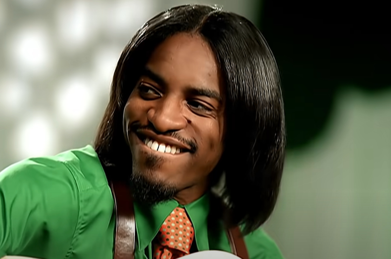 André 300 smiling and playing the guitar in the Hey Ya music video