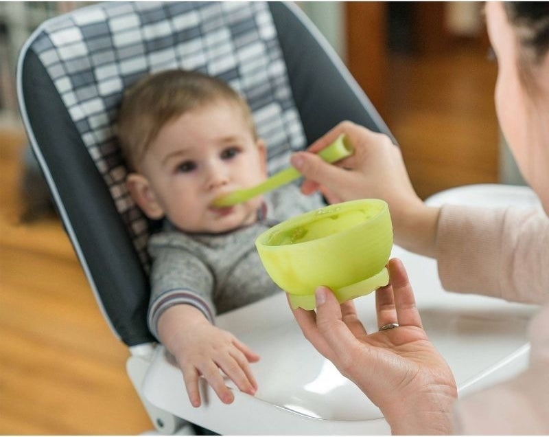 Parent feeds baby with spoon and bowl set