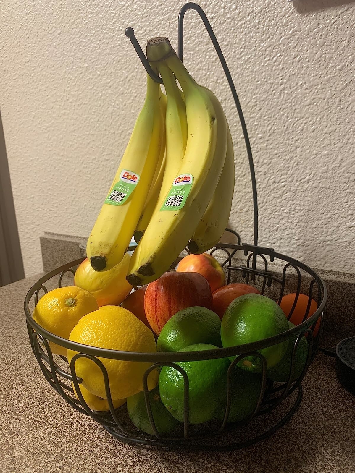 Reviewer's fruit bowl with apples, lemons, and limes and bananas hanging from hook