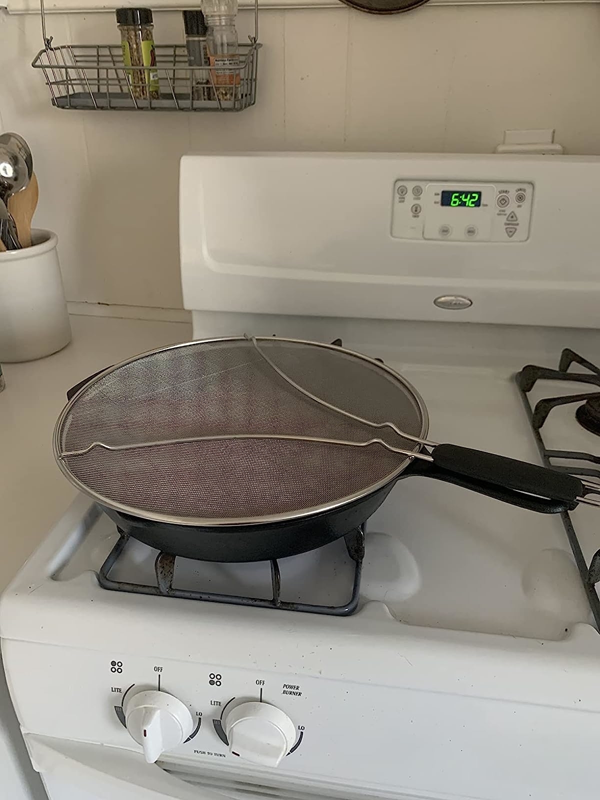 Reviewer image of the splatter guard on a frying pan on their stove