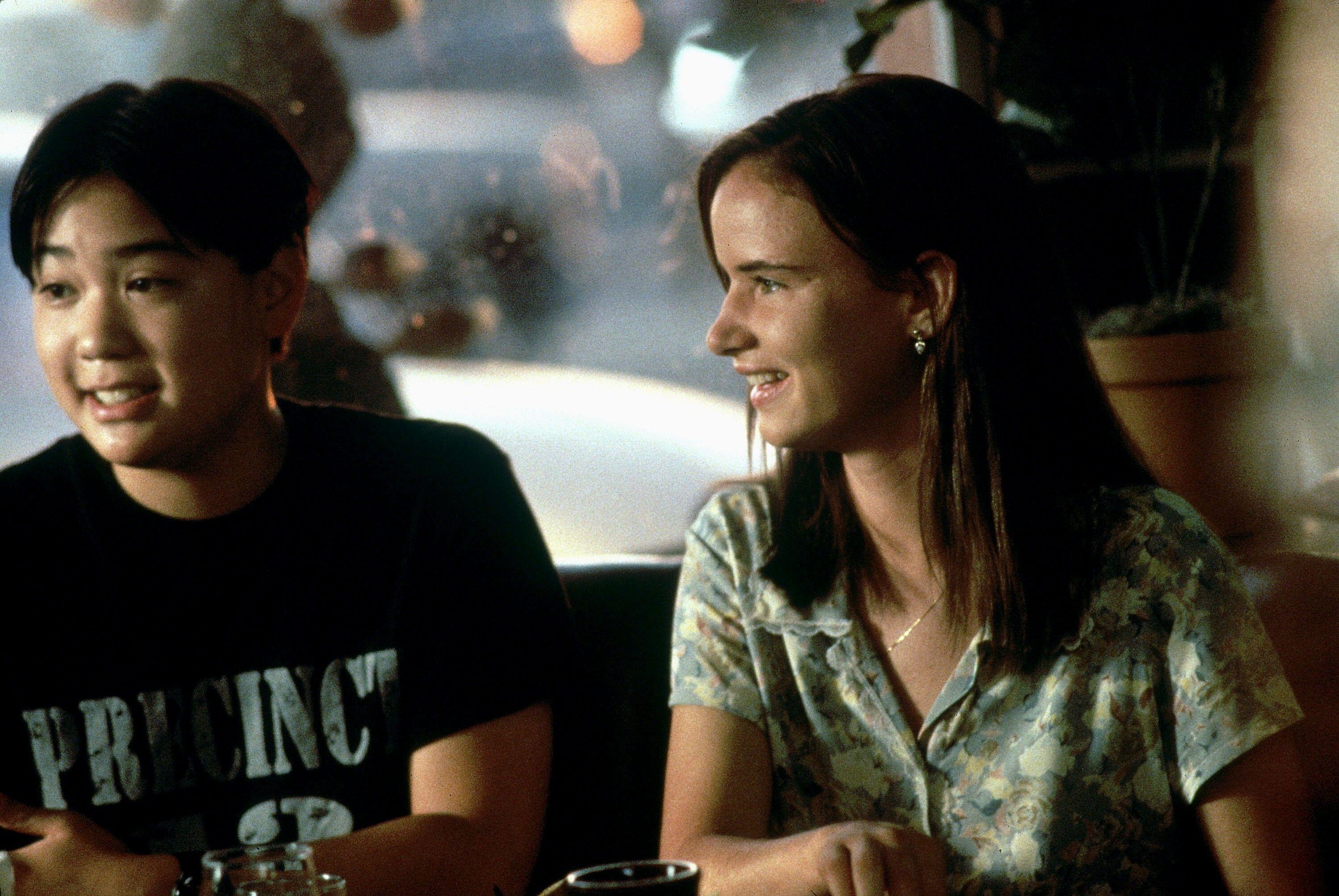 Ernest Liu &amp;amp; Juliette Lewis smile as they sit next to each other at a diner