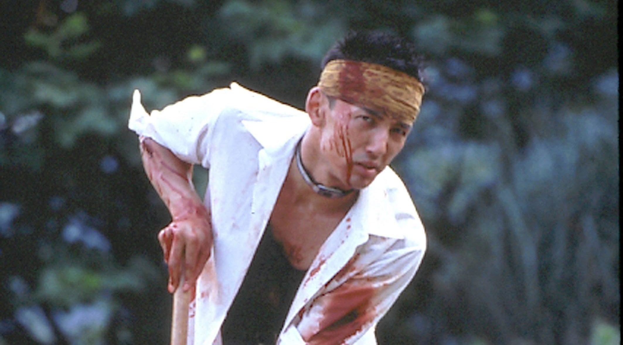 A bloodied Taro Yamamoto stumbles while holding a walking stick