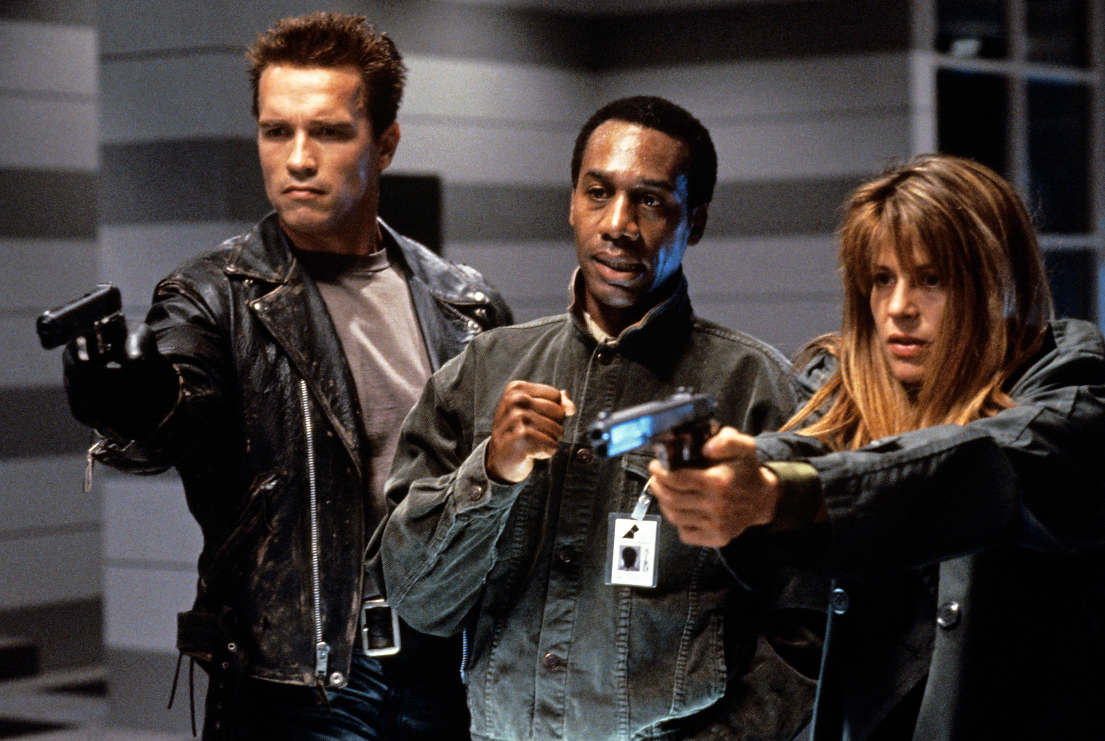 Arnold Schwarzenegger, Joe Morton, and Linda Hamilton engage in a stand-off with off-screen enemies