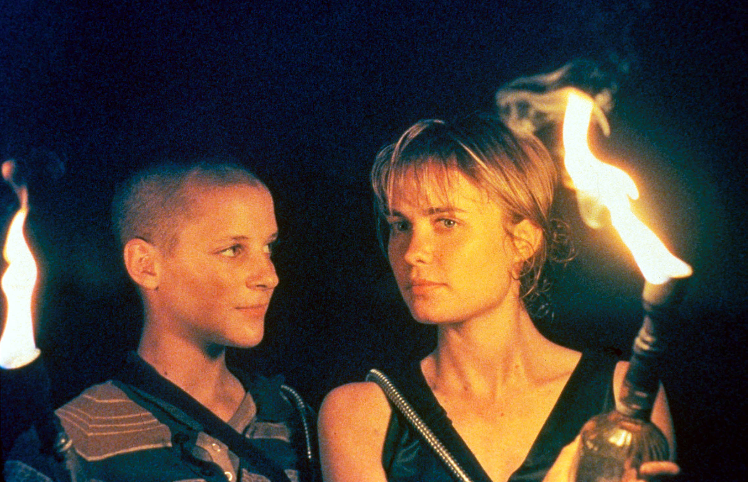 Rhiana Griffith and Radha Mitchell are illuminated by lit torches