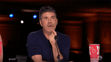 Gif of Simon Cowell on America&#x27;s Got Talent pursing his lips and thinking