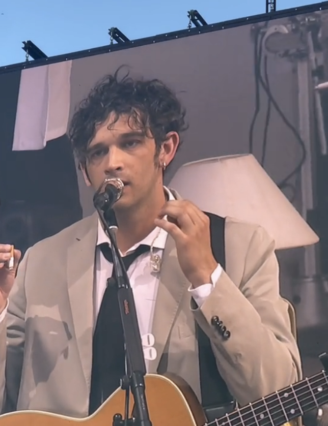 Closeup of Matty Healy onstage in a suit and tie