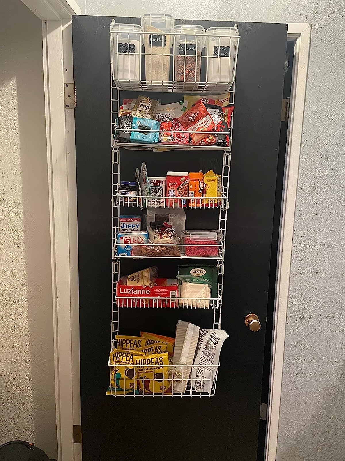 Reviewer's rack hanging on back of pantry door with dried goods and snacks on shelves