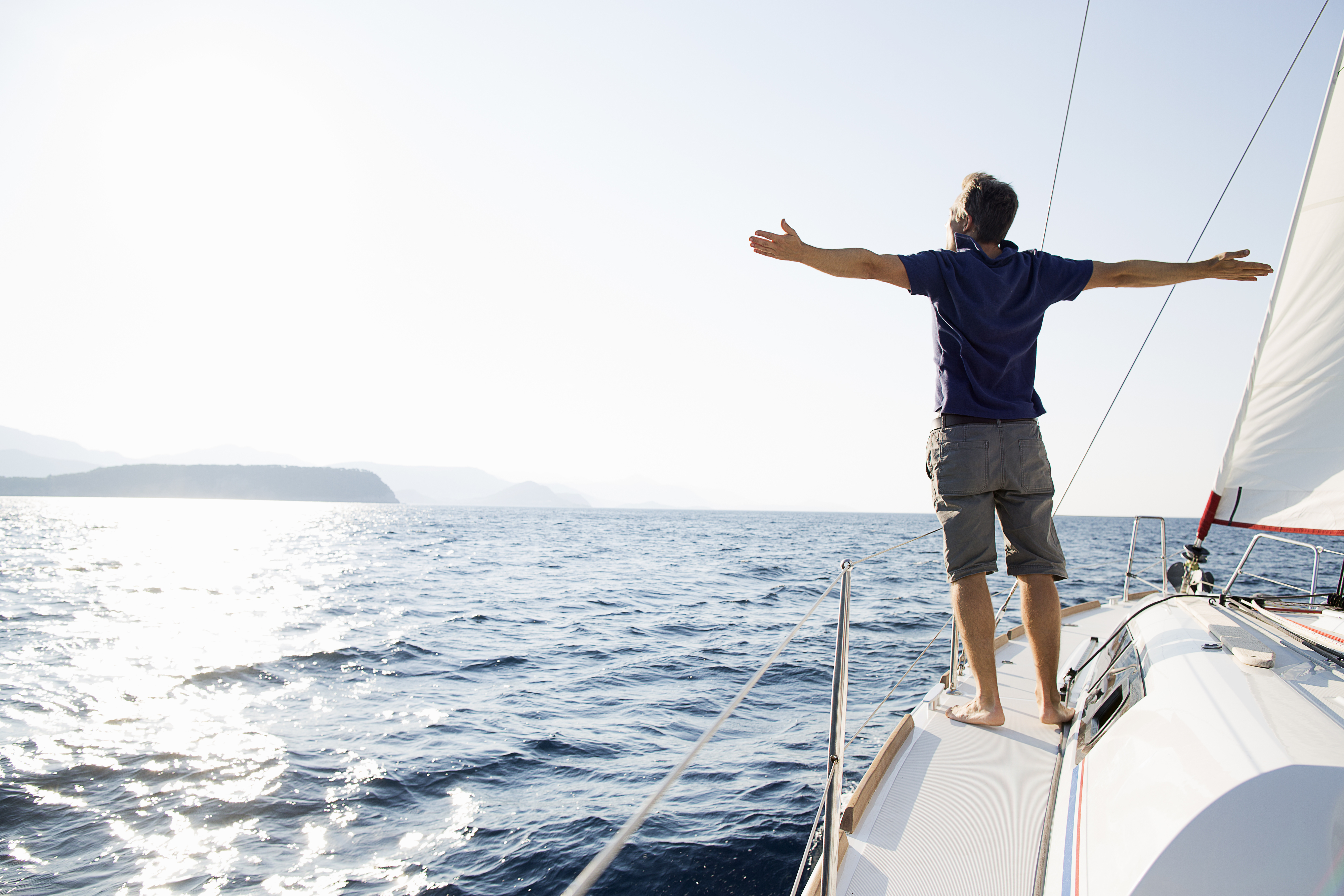 A man opens his arms wide while sailing on a sunny day