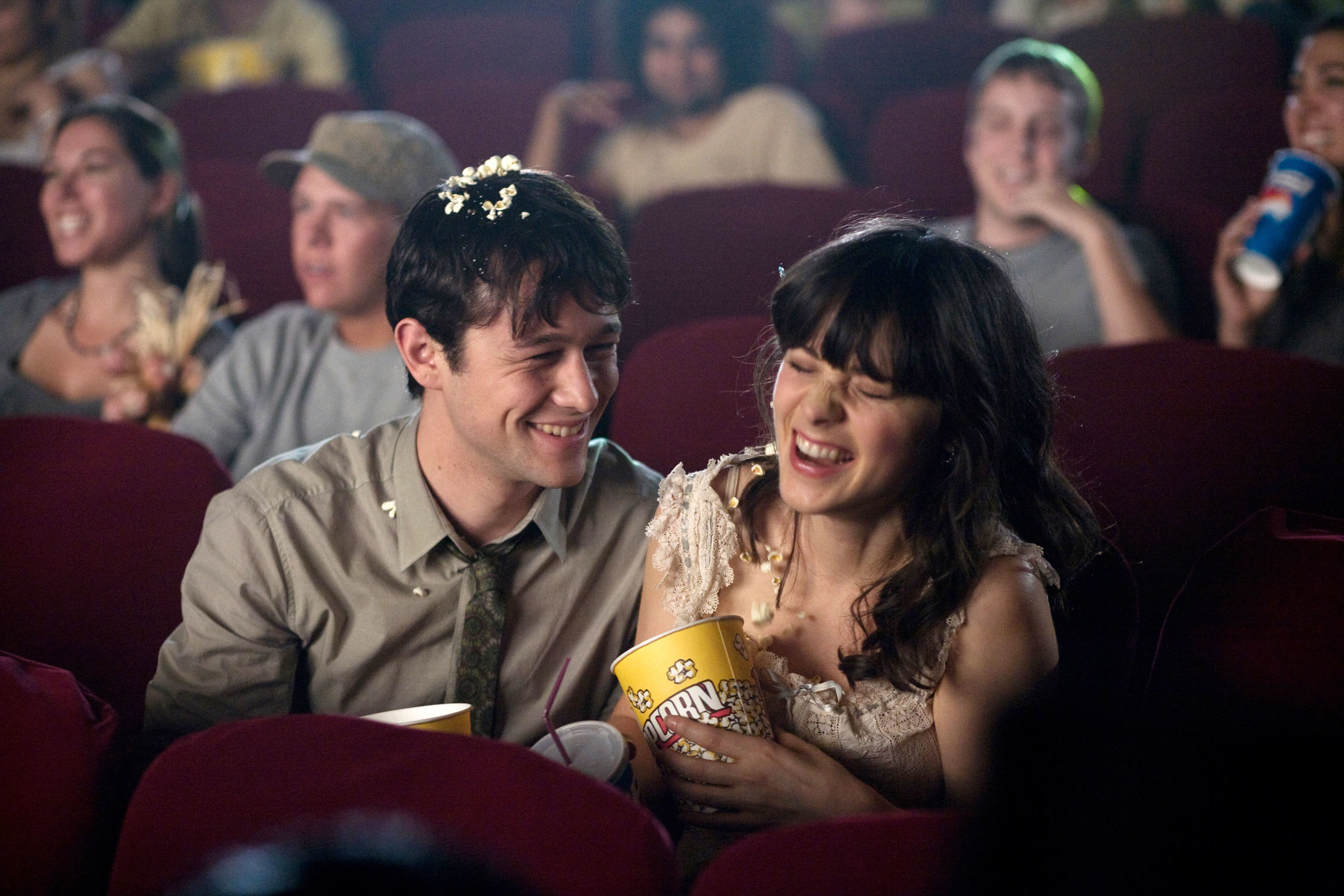 Joseph Gordon-Levitt and Zooey Deschanel laughing in a movie theater in (500) Days of Summer