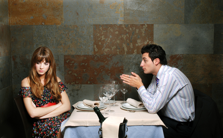 A woman looking disinterested on a date with a man