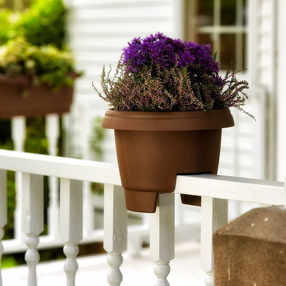 The balcony planter on a white deck rail with a purple flowering plant in it