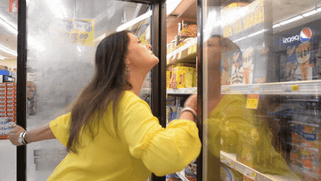 woman trying to cool down during a hot flash by sticking her face in the freezer