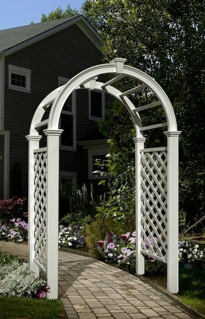 the white garden arbor with a trellis on either side in a garden