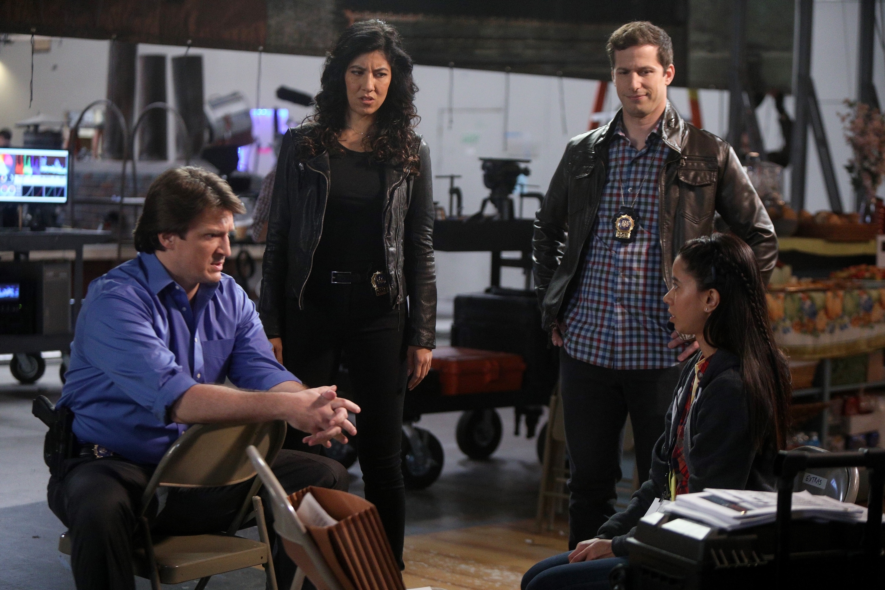 Nathan Fillion, Stephanie Beatriz and Andy Samberg interrogate a crew member on a film set