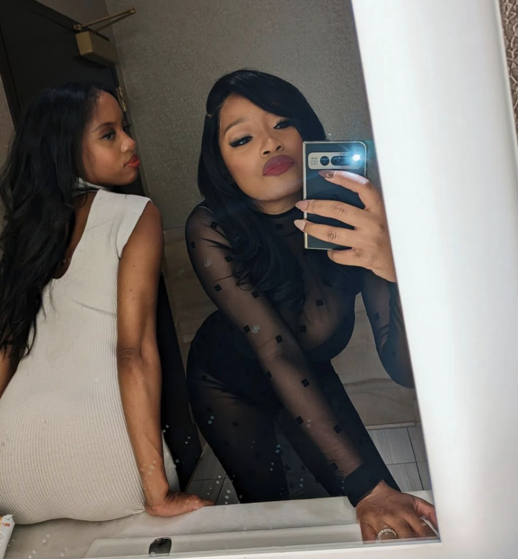 Keke wearing a diaphanous outfit in a selfie with a friend in front of a mirror