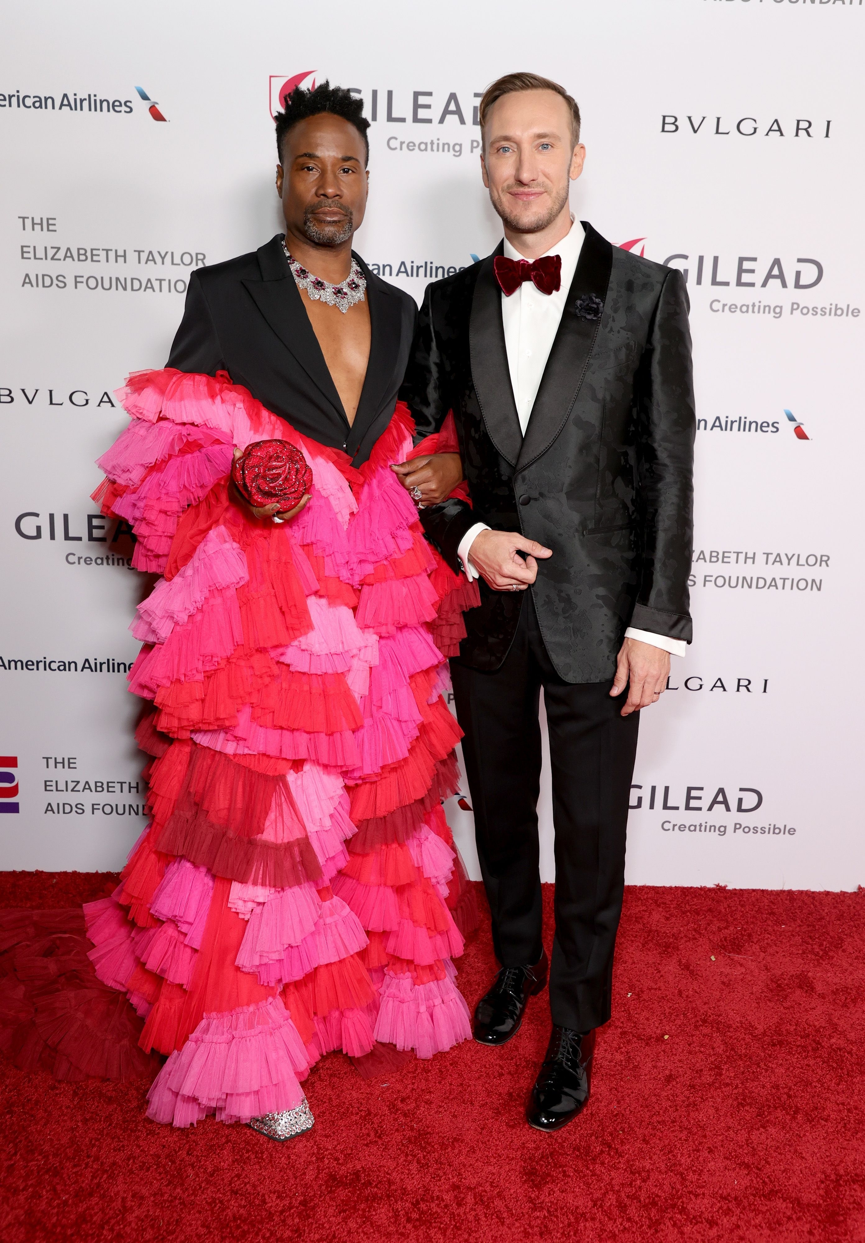 Billy, in a multitiered colorful outfit, and Adam, in a tux, arm in arm on the red carpet