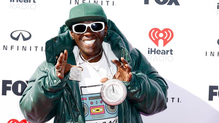 Flavor Flav holds up jewelry as he attends the 2023 iHeartRadio Music Awards.