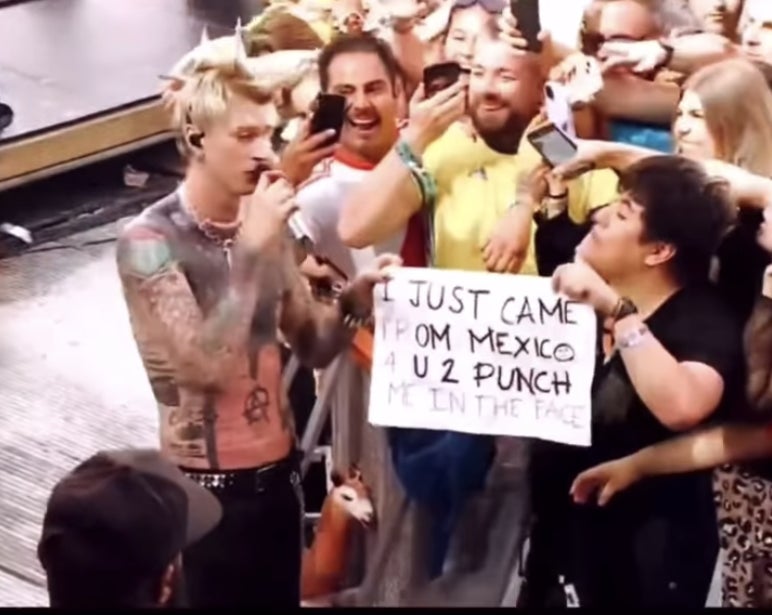 MGK holds up the sign with the fan in the crowd