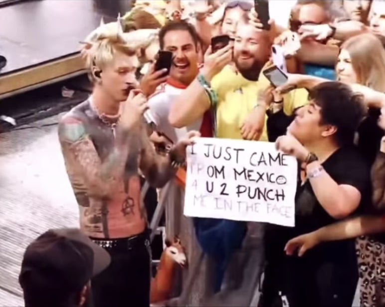 MGK holds up the sign with the fan in the crowd