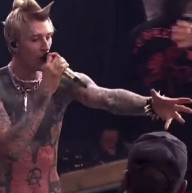 MGK holding out his arm toward the fan