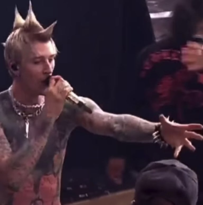 MGK holding out his arm toward the fan