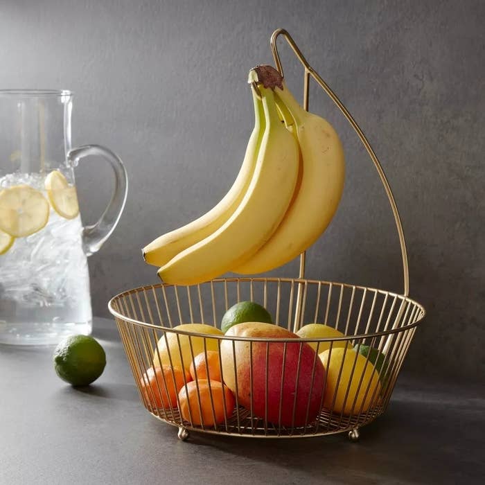 The metal wire basket filled with fruit and with bananas on the hanger.