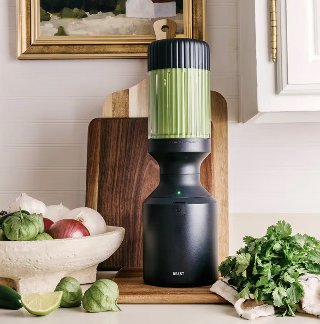 A black smoothie maker with green juice in it