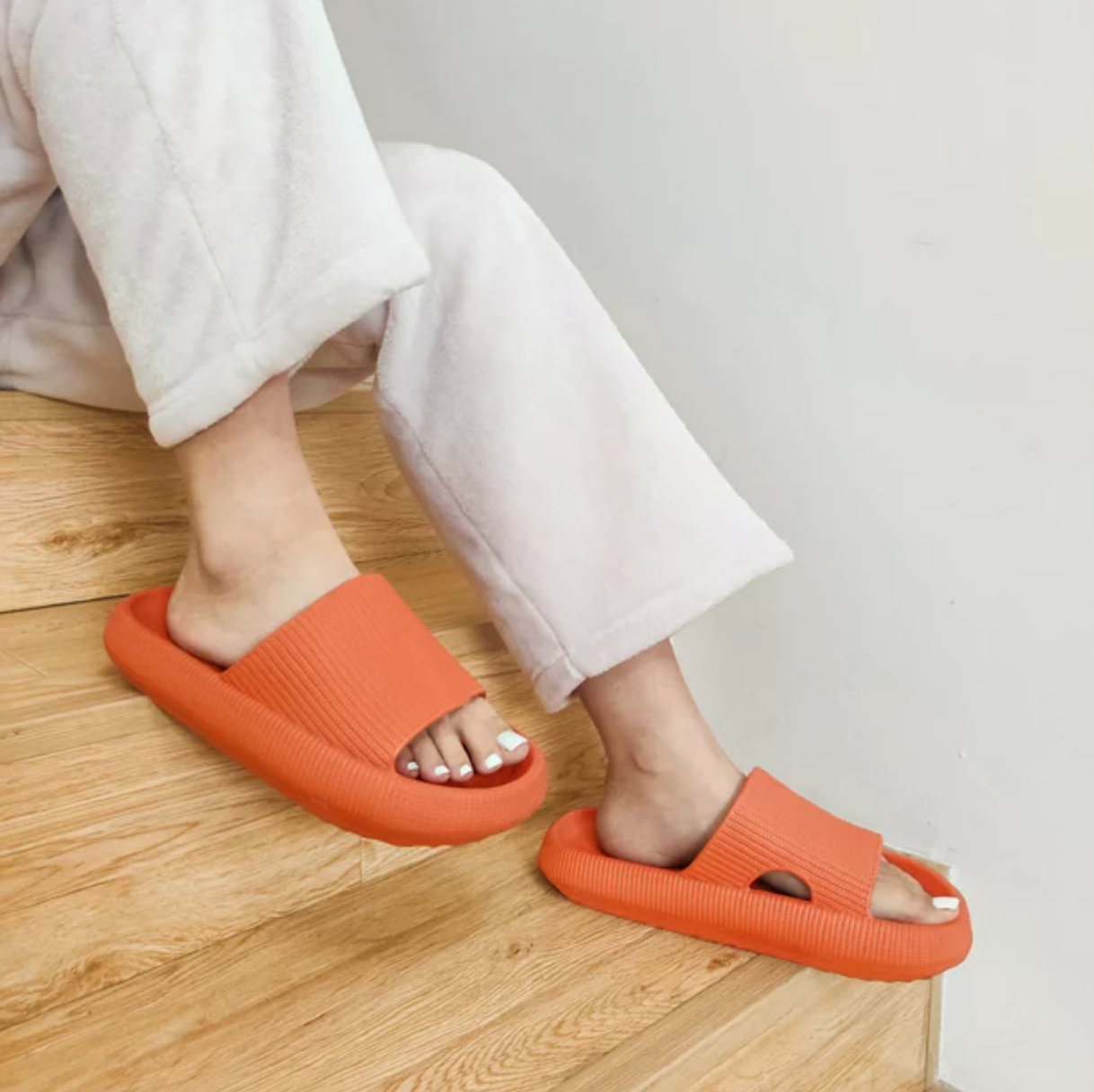 a model wearing the orange puffy slip on shoes