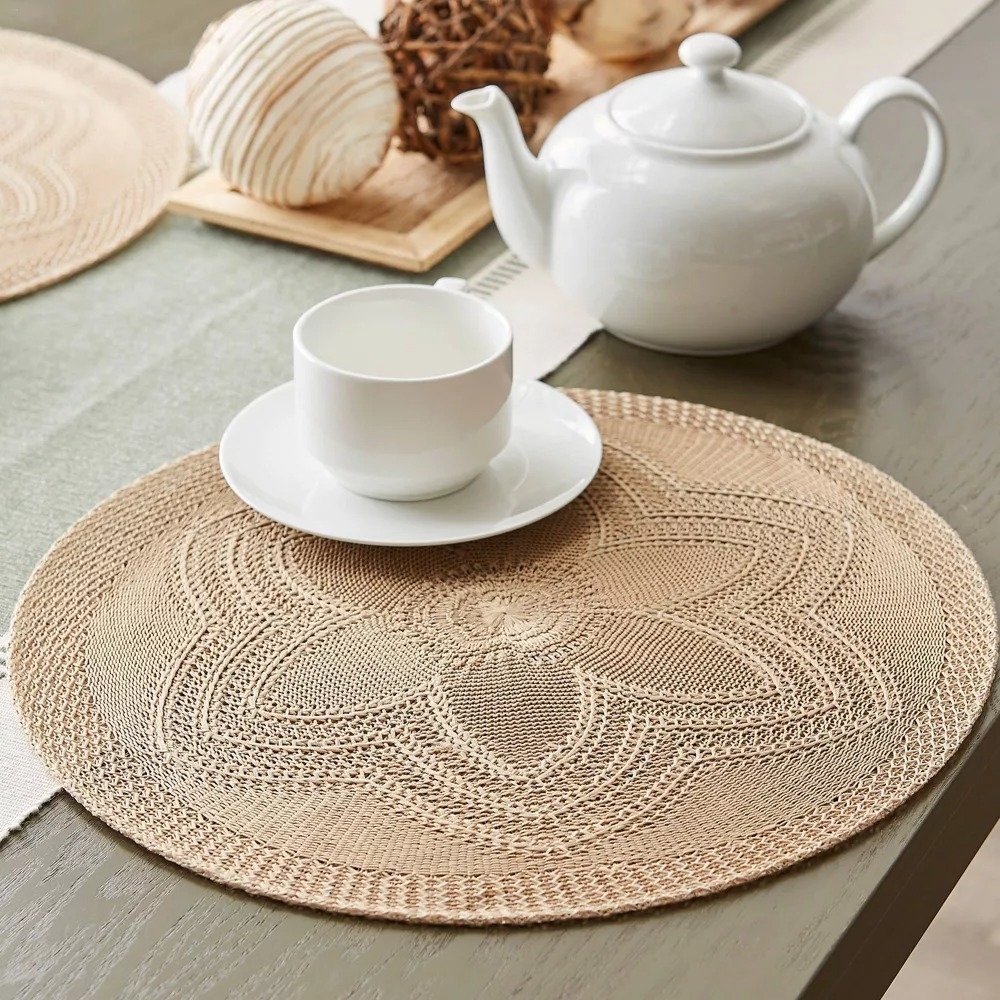 The placemats in beige placed on a table underneath a tea pot and cup.