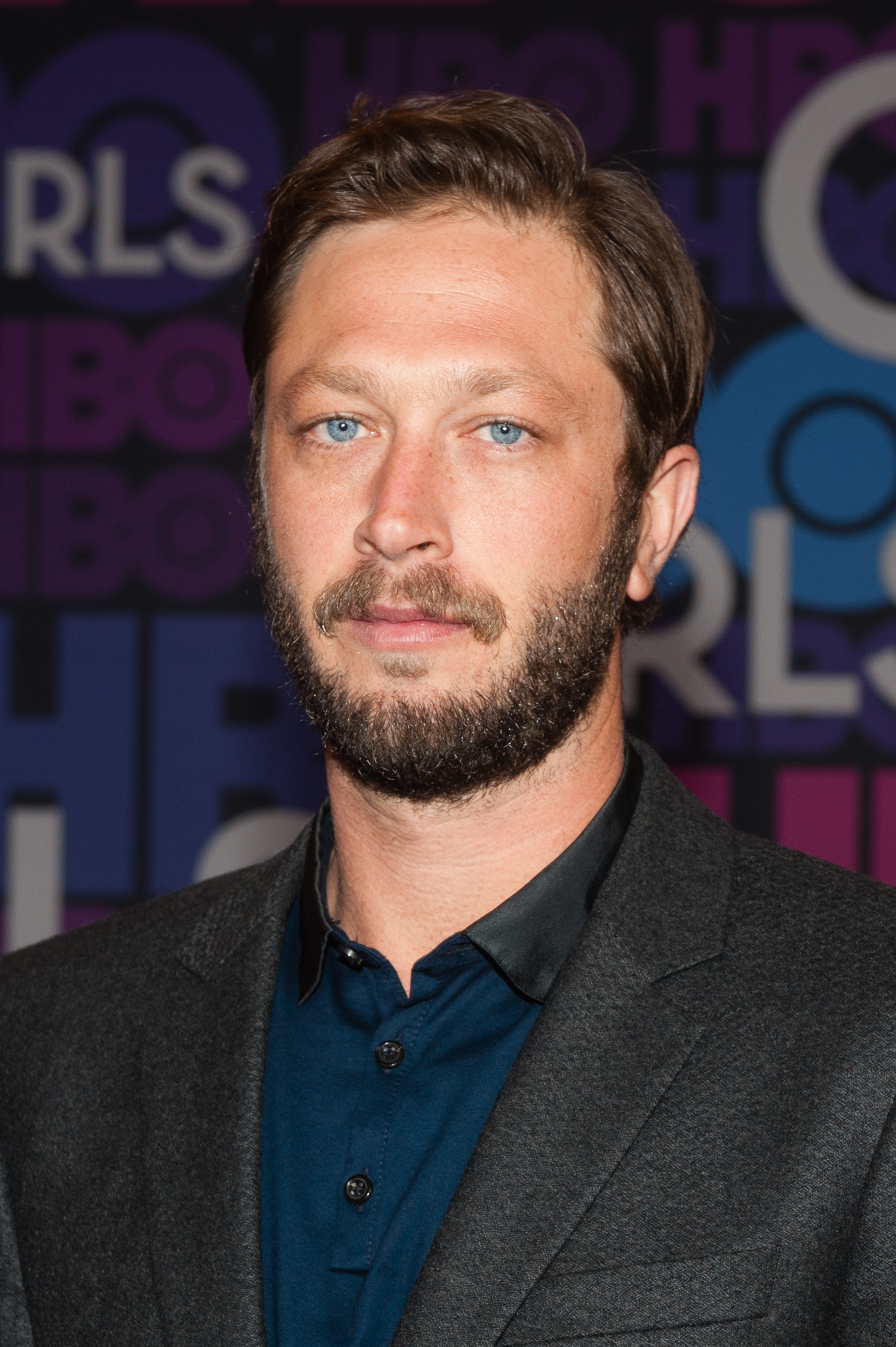 Ebon Moss-Bachrach in a blazer and collared shirt at the Girls Season 4 premiere. He had a beard and short styled hair