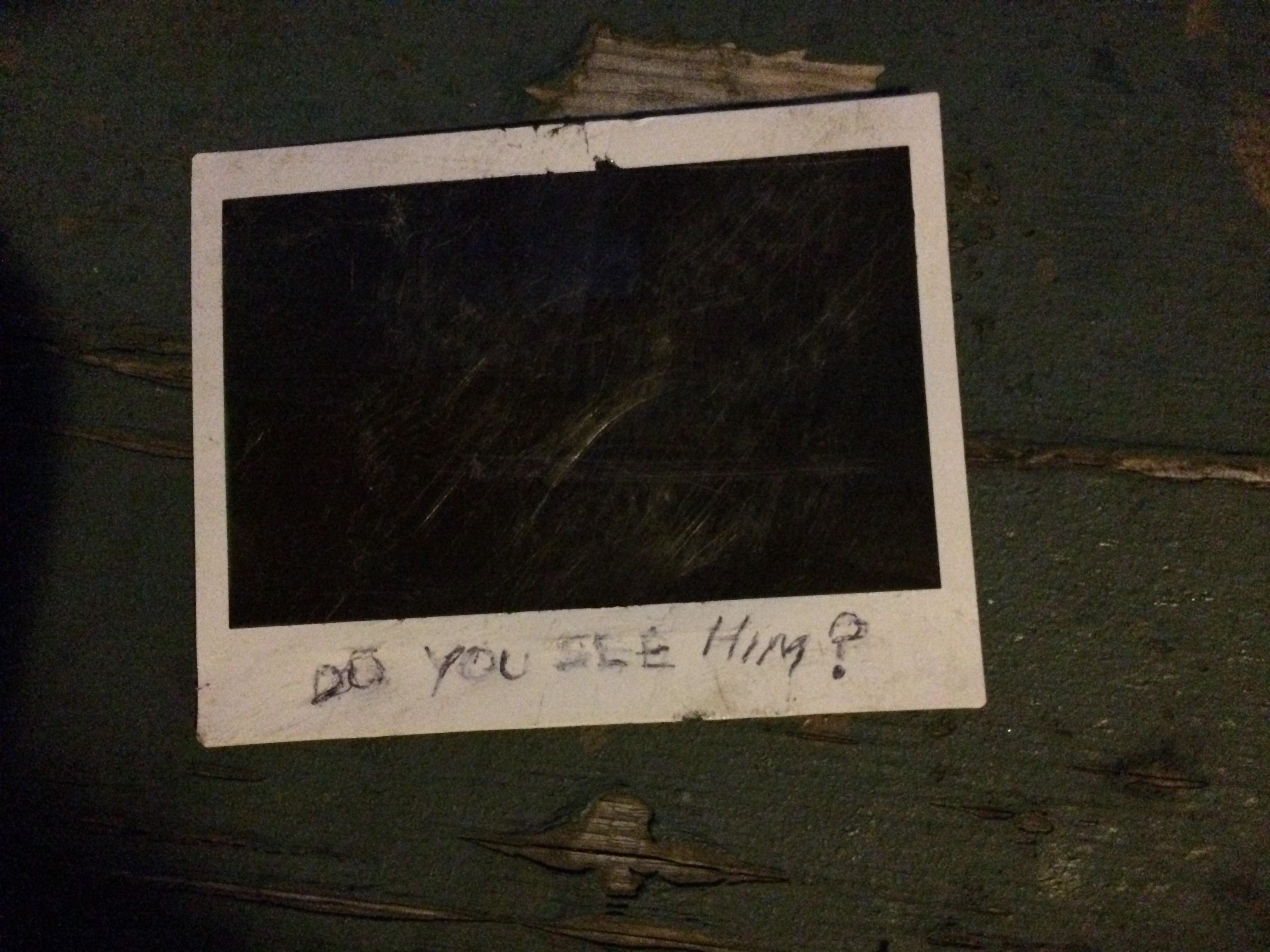 An imperceptible Polaroid with words written in pen &quot;Do you see him?&quot; on it
