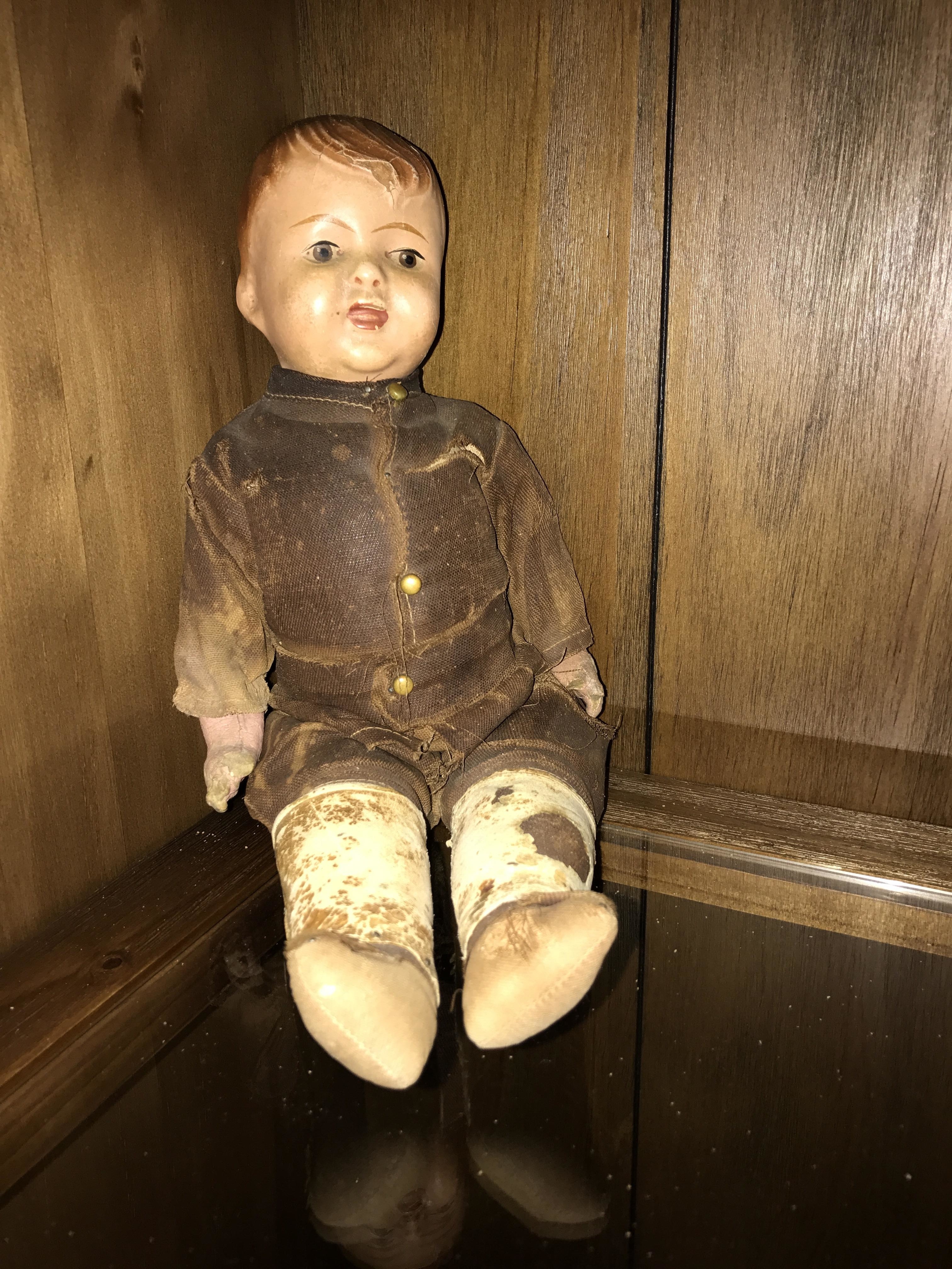 A creepy old doll sitting on a shelf