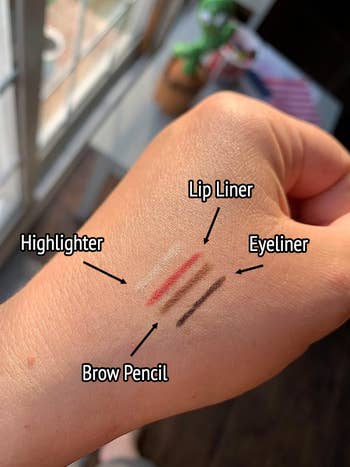 A swatch on the reviewers hand with the highlighter, mauve lipliner, brown brow pencil, and eyeliner