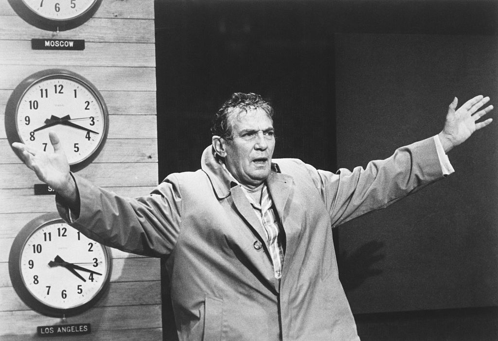 Finch in promotional still photo dressed in a trench coat and sweaty on the set of Network