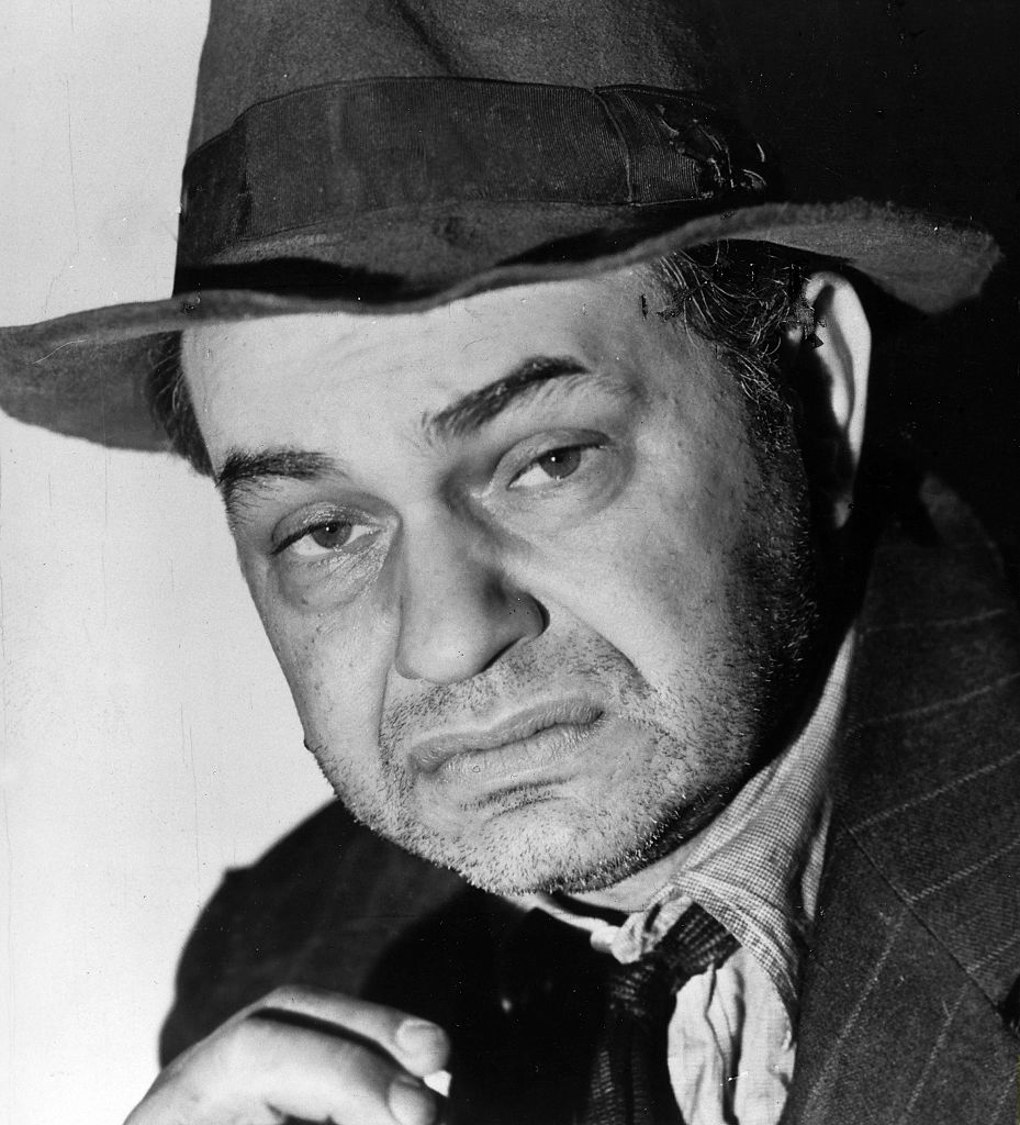 Robinson as a younger man wearing a suit and hat with scruff on his face