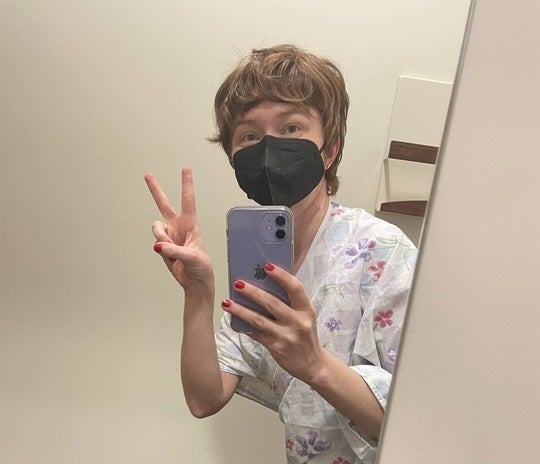 the author posing for a mirror selfie wearing one of those awful medical gowns