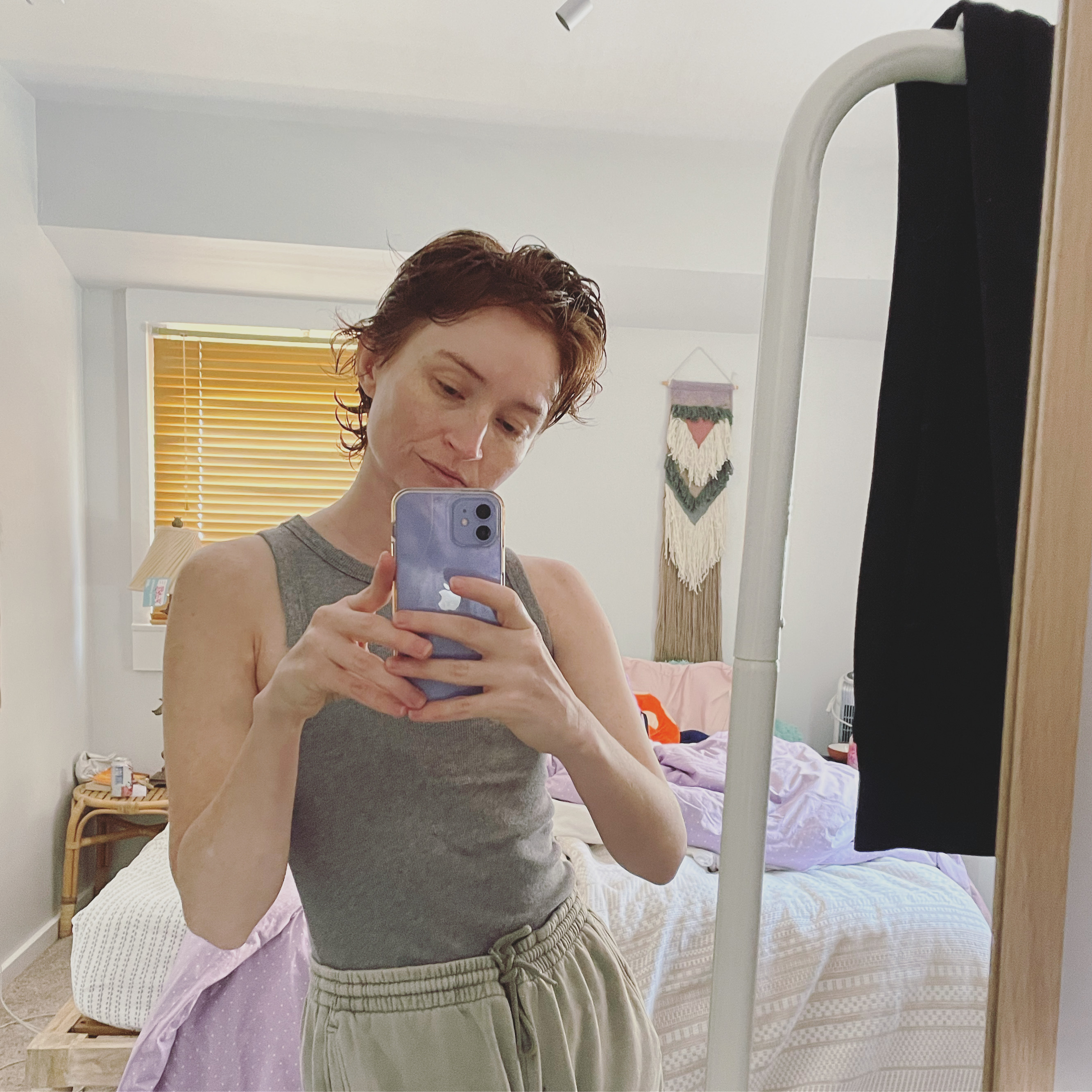 the author taking a mirror selfie in her bedroom wearing a tank top and sweatpants