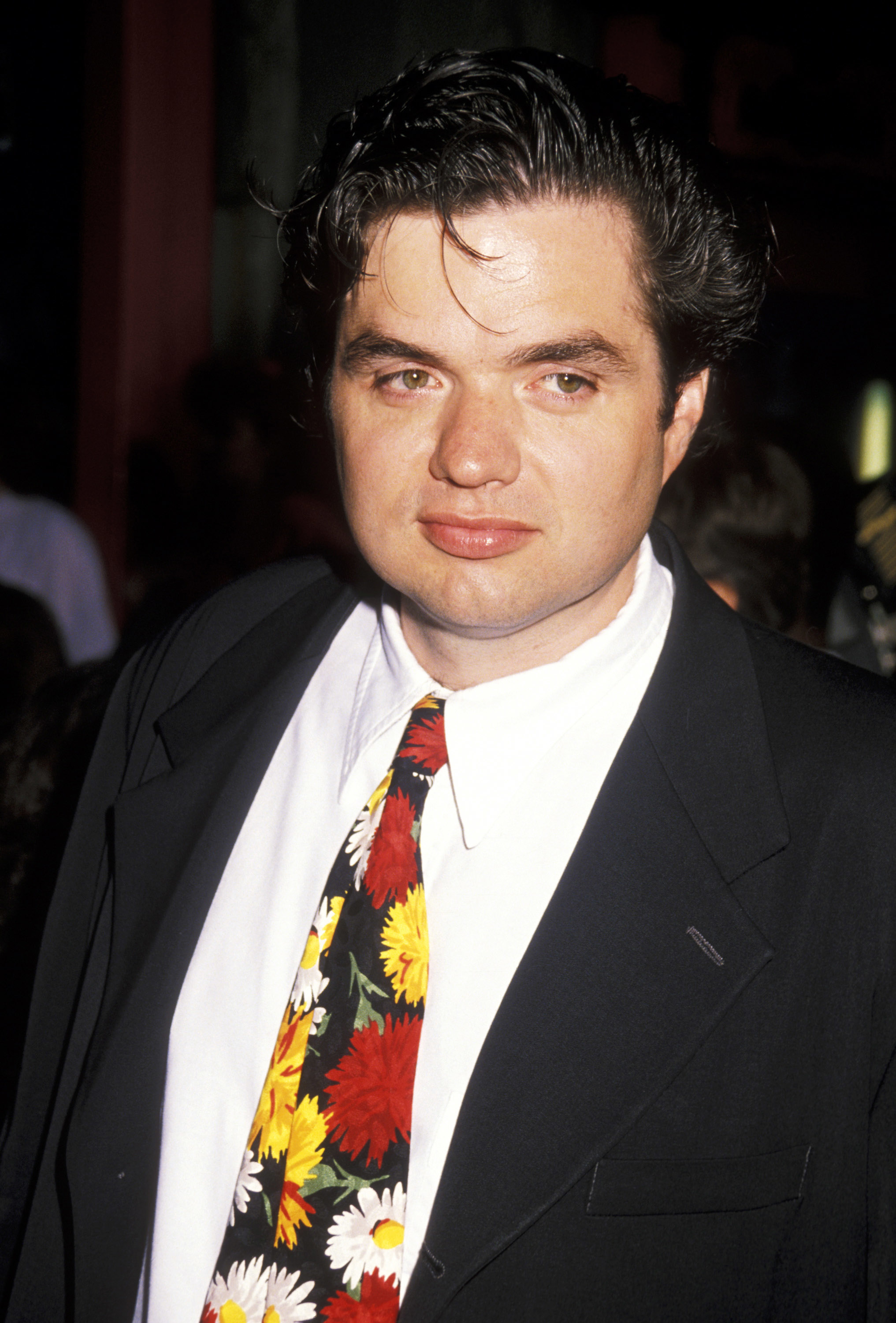 Oliver Platt at a premiere wearing a floral tie, suit jacket, and dress shirt