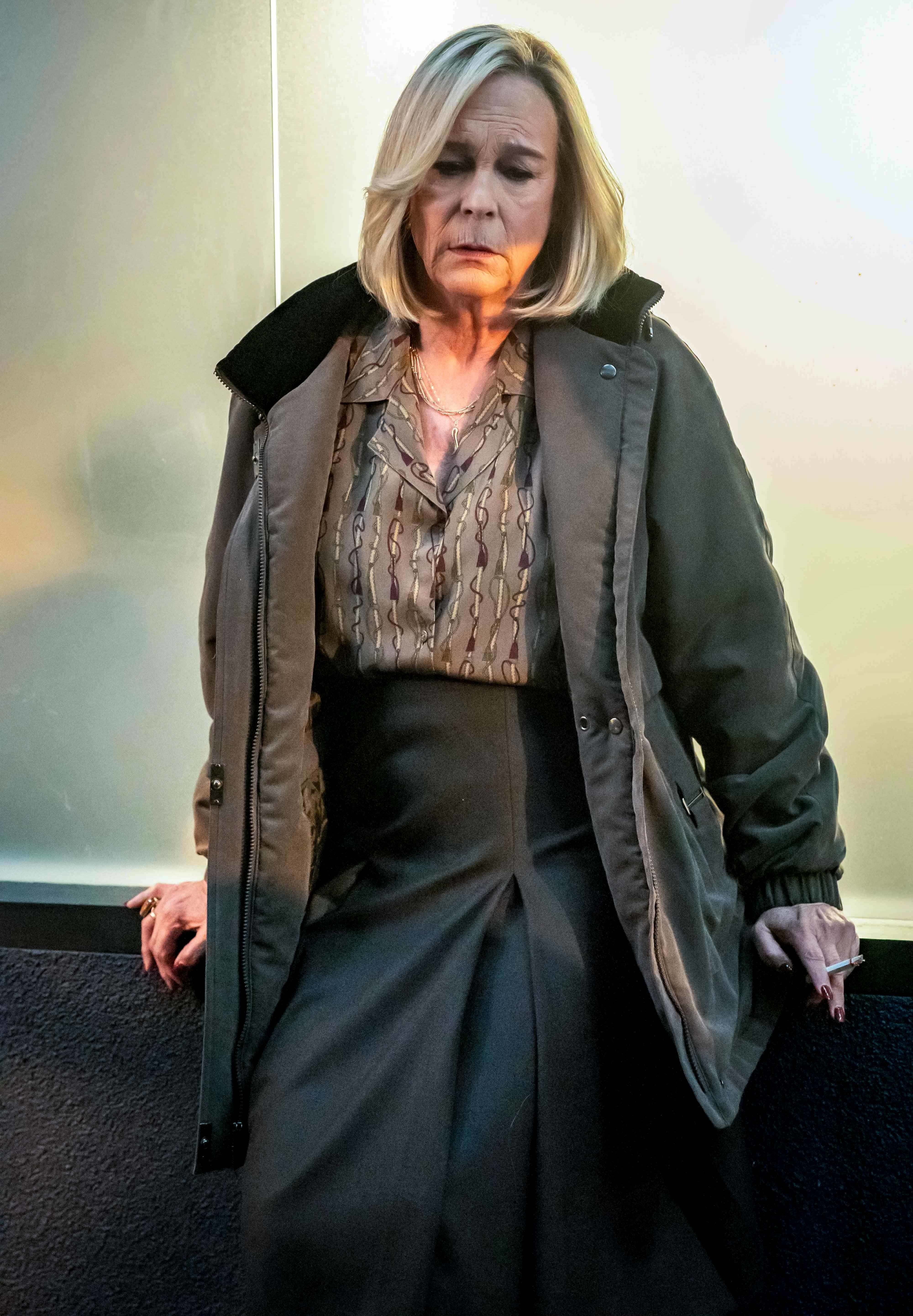 Jamie Lee Curtis looking distressed in a long coat, skirt and button-up shirt in The Bear