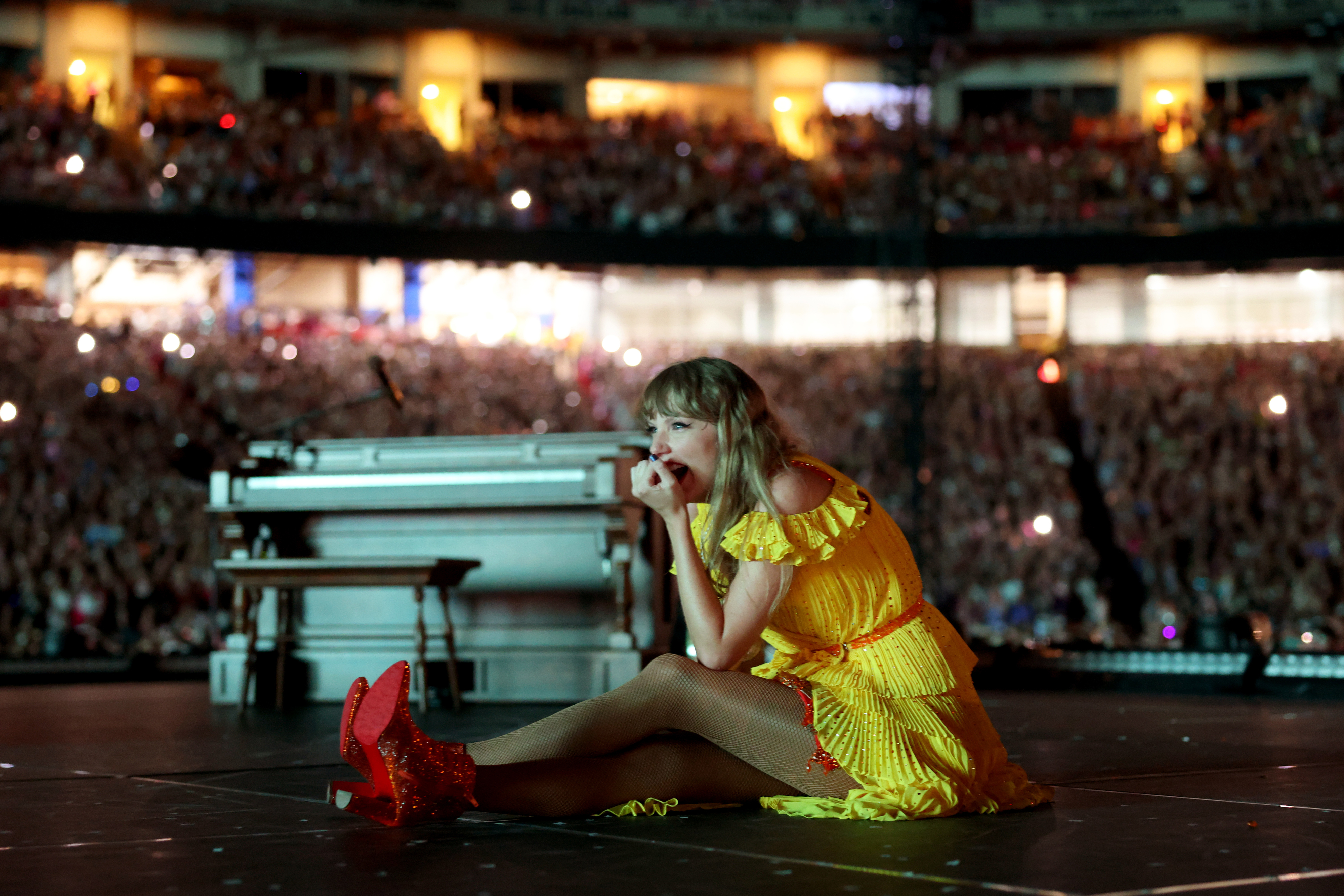 Taylor sitting on stage to watch the video with fans
