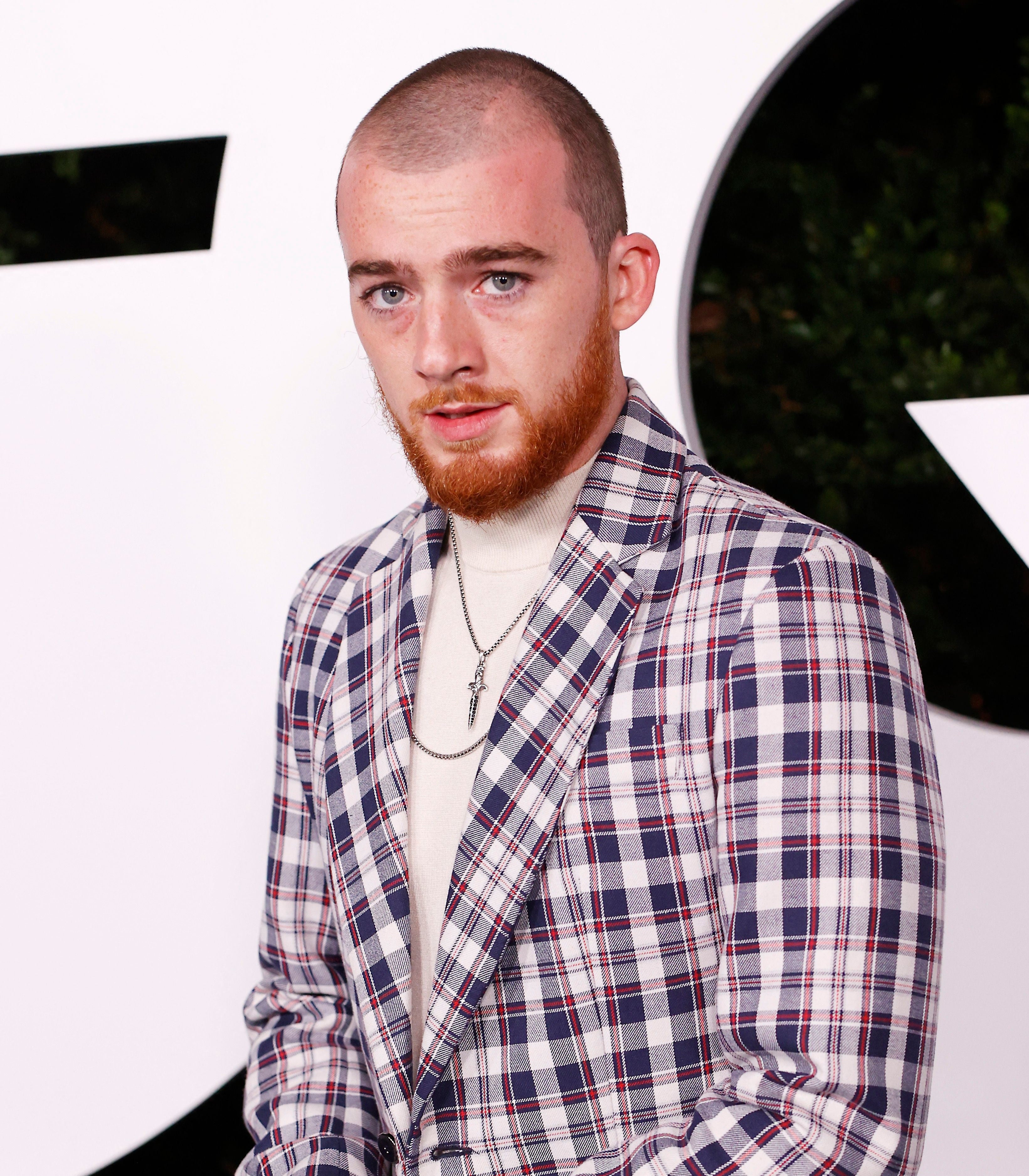 Close-up of Angus in a plaid jacket at a press event