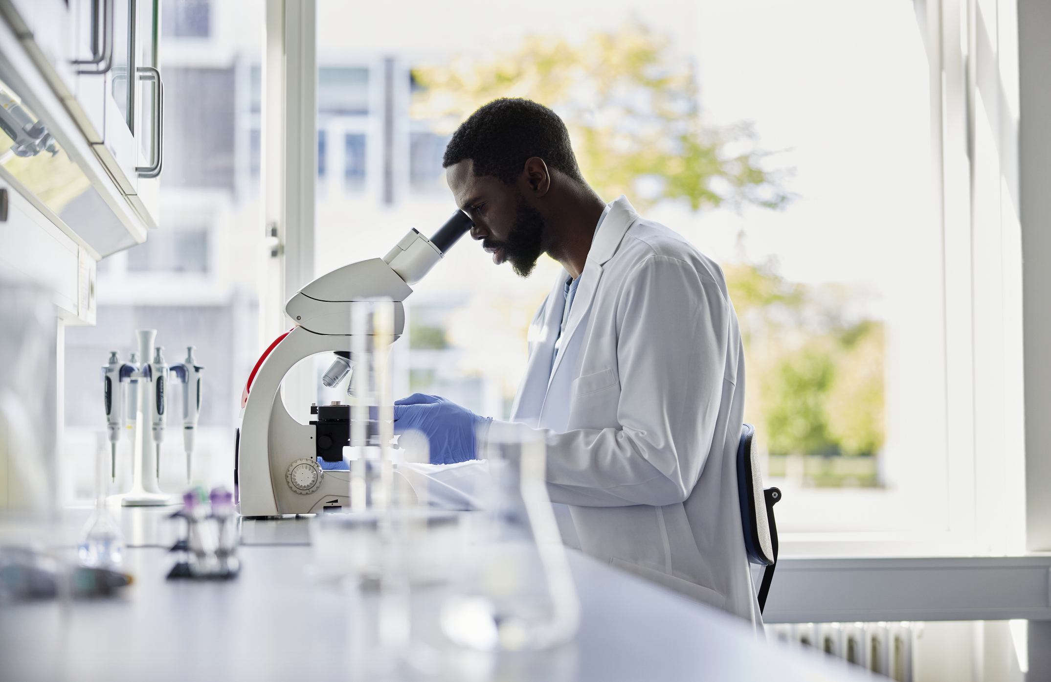 A man in a lab coat looking in a microscope